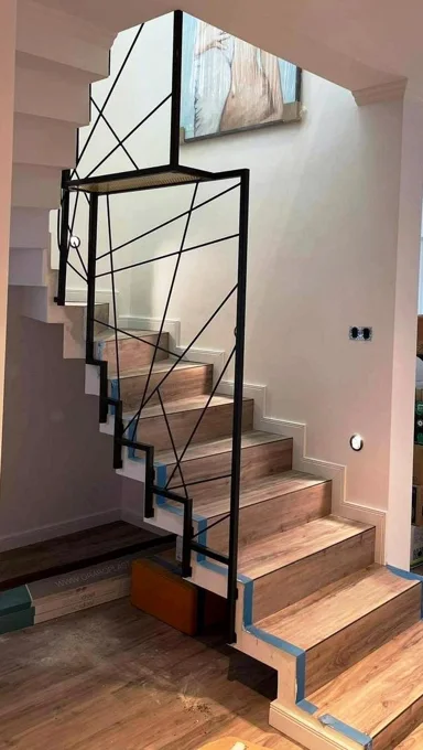 Geometrinis juodas turėklas prie medinių laiptų